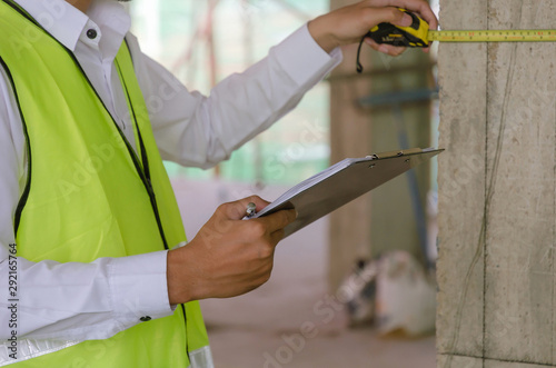 Construction. young foreman builder, engineer or inspector checking and inspecting with clipboard and measuring tape at construction site building interior project, contractor and engineering concept