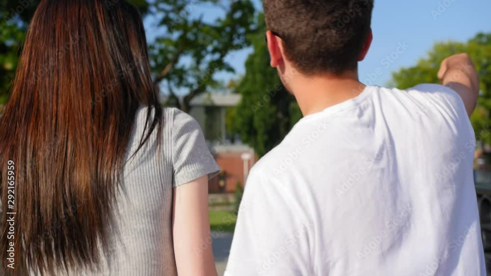 Back view of happy couple walking outdoor and talking together in park. Couple Trust, Love and Happiness concept. Close up shot. Back view of happy couple walking outdoor and talking together in park. Couple Trust, Love and Happiness concept. Close up shot.