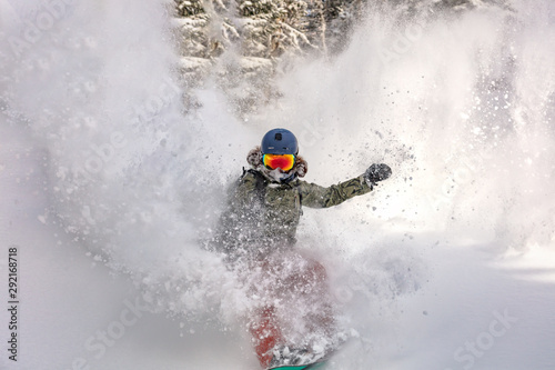 female snowboarder curved and brakes spraying loose deep snow on the freeride slope. downhill with snowboards in fresh snow. freeride world champion.