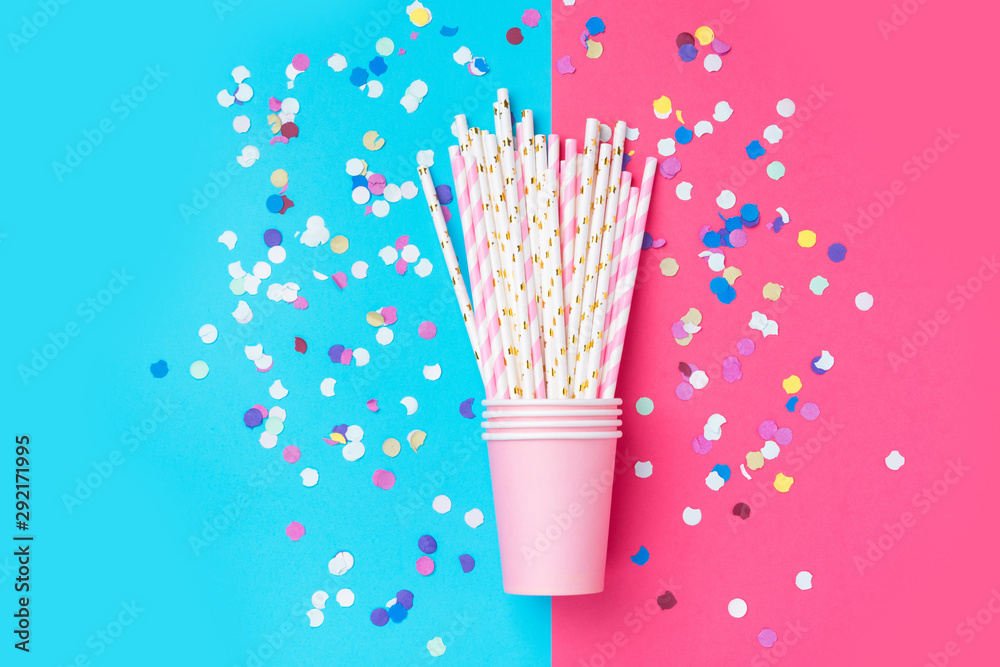 Stacked drinking paper cup striped straws colorful confetti scattered on bright duotone fuchsia blue background. Flat lay composition birthday party celebration kids fun. Greeting card poster template Stacked drinking paper cup striped straws colorful confetti scattered on bright duotone fuchsia blue background. Flat lay composition birthday party celebration kids fun. Greeting card poster template