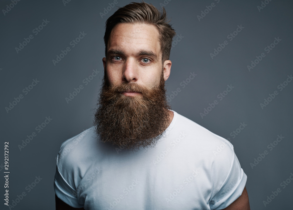 Obraz premium Bearded young man standing confidently against a gray background