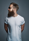 Stylish young man with a beard wearing sunglasses looking sideways