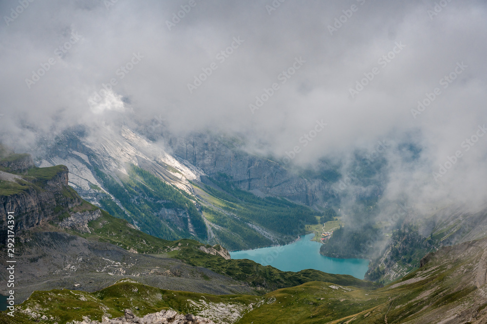 landscape at Hohtürli with Oeschinensee in the distance in misty clouds while hiking