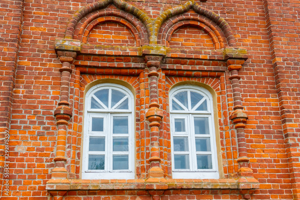 Two rounded windows on old red brick wall