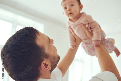 Cute baby girl being held aloft by her father