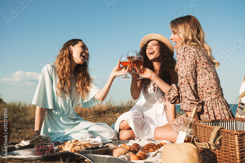 Obraz na płótnie Photo of amazed young women drinking red wine while having picnic