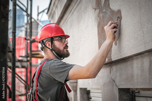 Foto Man worker standing on scaffolding and restore old building facade
