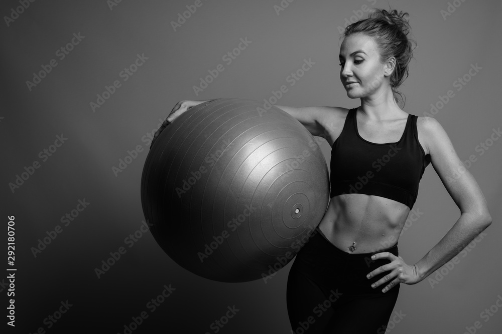 Young beautiful woman ready for gym against gray background Young beautiful woman ready for gym against gray background