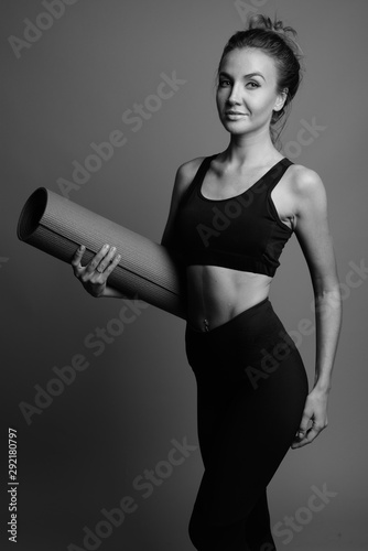 Young beautiful woman ready for gym against gray background © Ranta Images