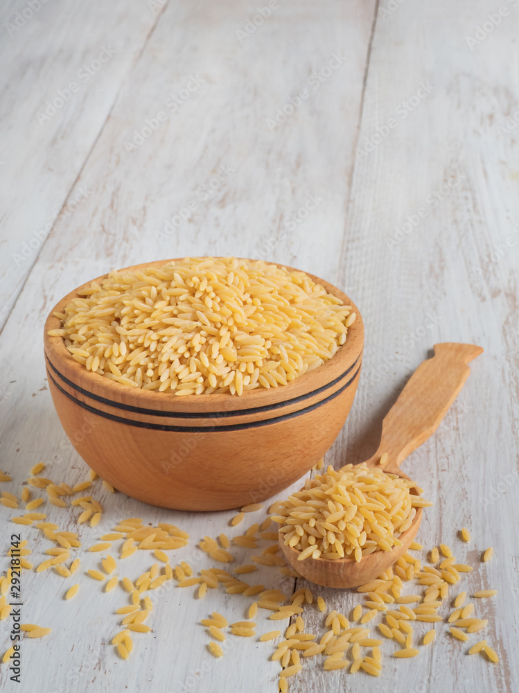 Orzo (risoni) pasta in wooden bowl. Stock Photo | Adobe Stock