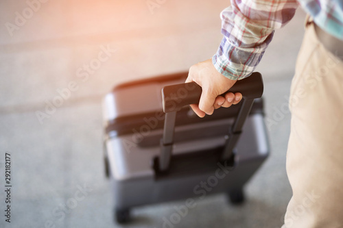 Fototapeta Naklejka Na Ścianę i Meble -  businessman walking outside public transport building with luggage in rush hour. Business traveler pulling suitcase in modern airport terminal. baggage business Trip.  Copy space , top view