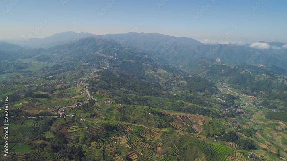 Aerial view of rice terraces and agricultural farm land on the slopes of mountains valley. Cultivation of agricultural products in mountain province. Mountains covered forest, trees. Cordillera region