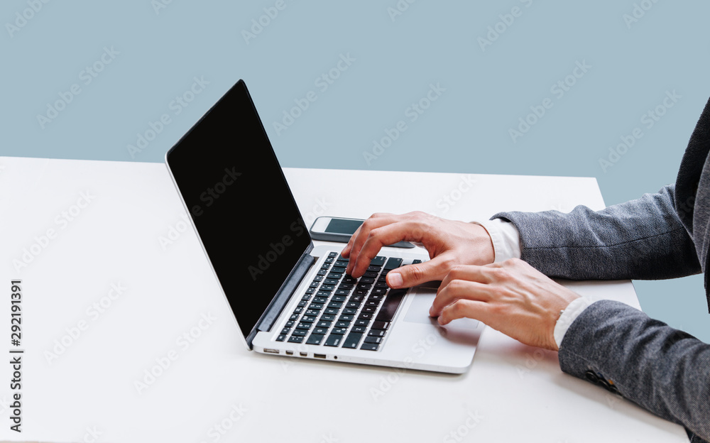 Businessman sitting behind the desk, working with laptop at office