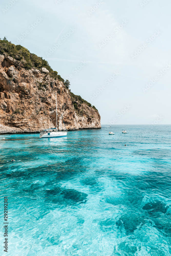 Boat floating in crystal clear water in Sardinia, Italy