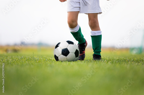 Child training soccer on fresh grass pitch. Soccer camp for kids. Boys practice dribbling in a field. Player develop dribbling skills. Boy in yellow shirt training with ball