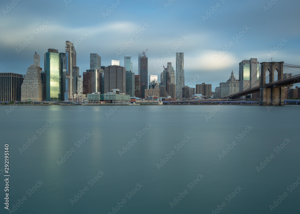 Obraz premium Financial District with Brooklyn bridge from east river at sunrise with long exposure