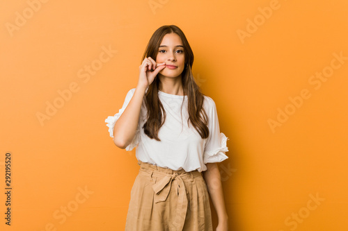 Photography Young caucasian woman with fingers on lips keeping a secret.