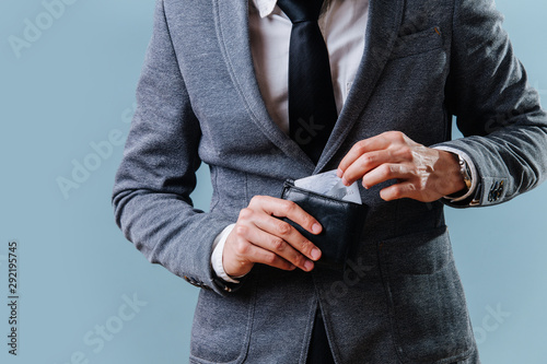 Businessman in a suit pulling credit card from his wallet over blue background