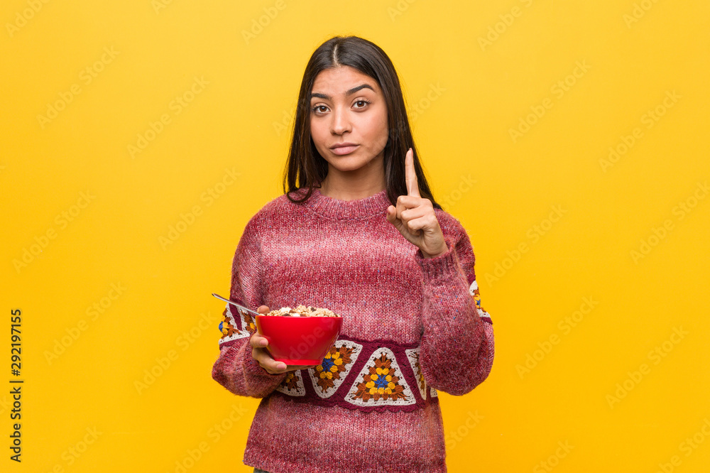 Young arab woman holding a cereal bowl showing number one with finger. Young arab woman holding a cereal bowl showing number one with finger.