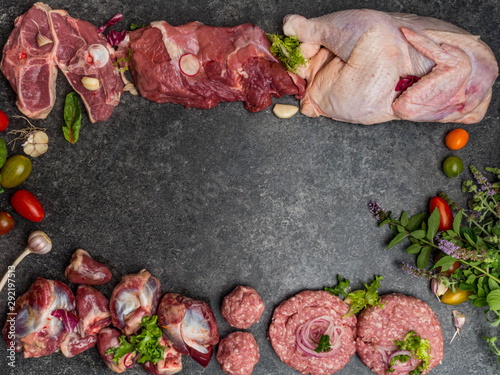Assorted raw meat on dark background. Different types of meat and processed food. Top view, vintage toned image, blank space