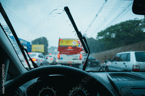 Driving a car in the rain. Inside view, driving on a traffic jam on a cold rainy day. Wet windscreen and wiper cleaning the glass. 
