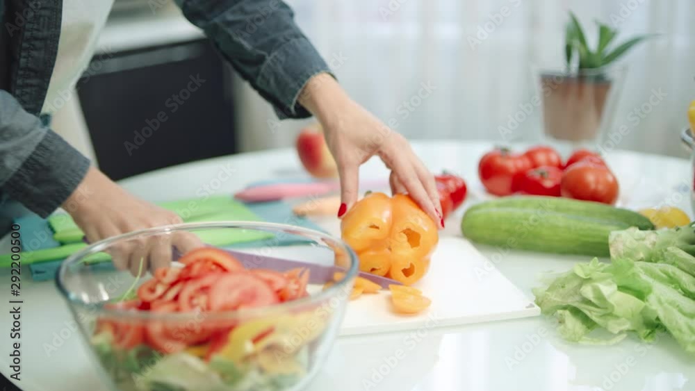 Woman cutting peppers with sharp knife in kitchen. Closeup hands slicing peppers Woman cutting peppers with sharp knife in kitchen. Closeup hands slicing peppers