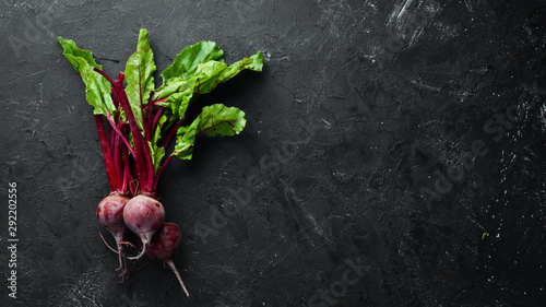 Fresh beetroot with leaves on a black stone background. Healthy food. Top view. Free space for your text.