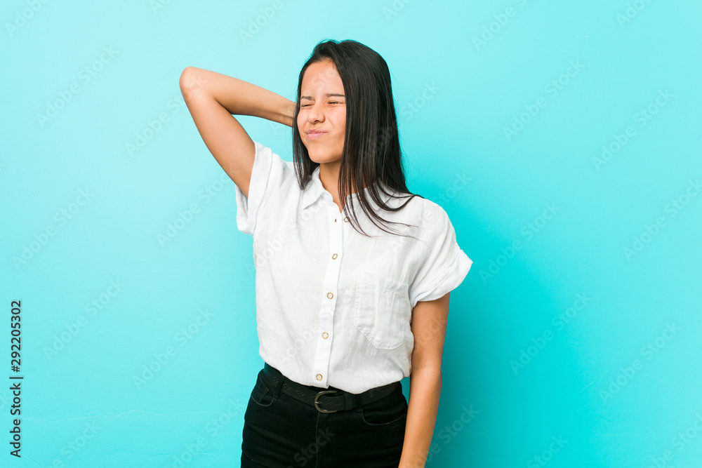 Young hispanic cool woman against a blue wall suffering neck pain due to sedentary lifestyle. Young hispanic cool woman against a blue wall suffering neck pain due to sedentary lifestyle.