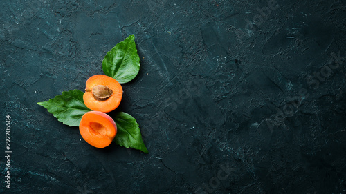 Fresh apricots with green leaves on a black background. Rustic style. Top view. Free space for your text. photo