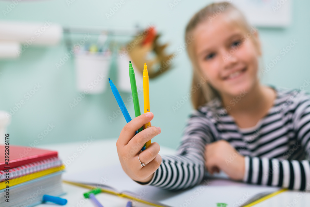 closeup of little girl holding felt pens