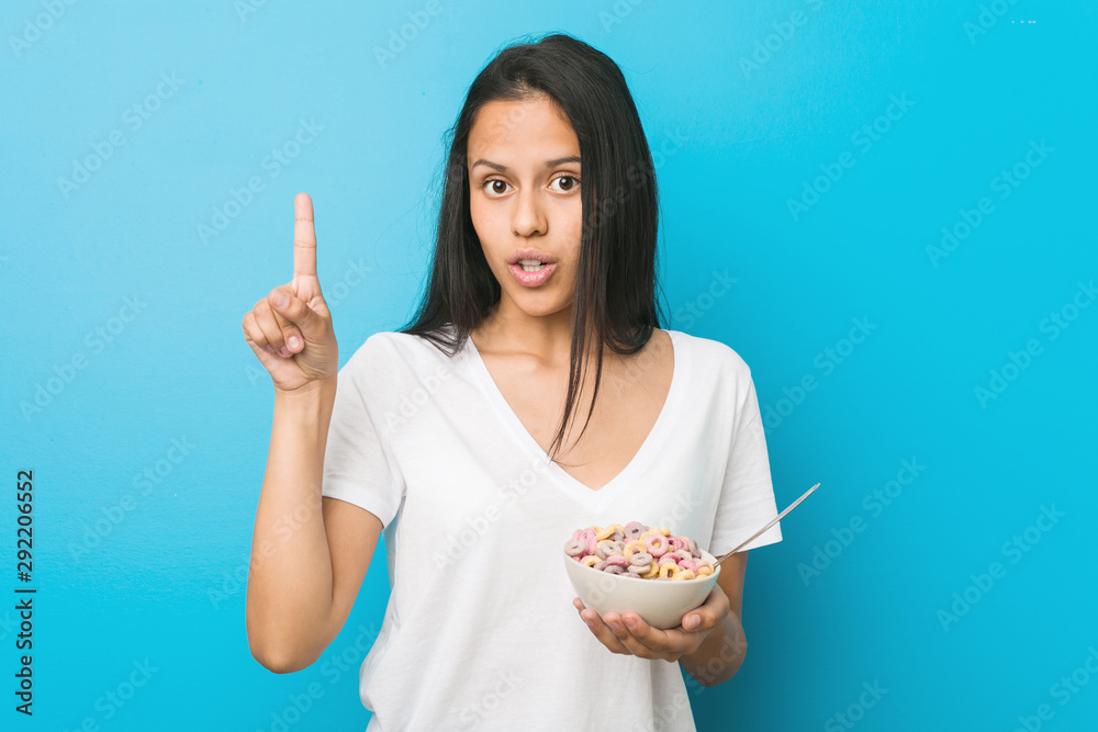 Young hispanic woman holding a sugar cereal bowl having some great idea, concept of creativity. Young hispanic woman holding a sugar cereal bowl having some great idea, concept of creativity.