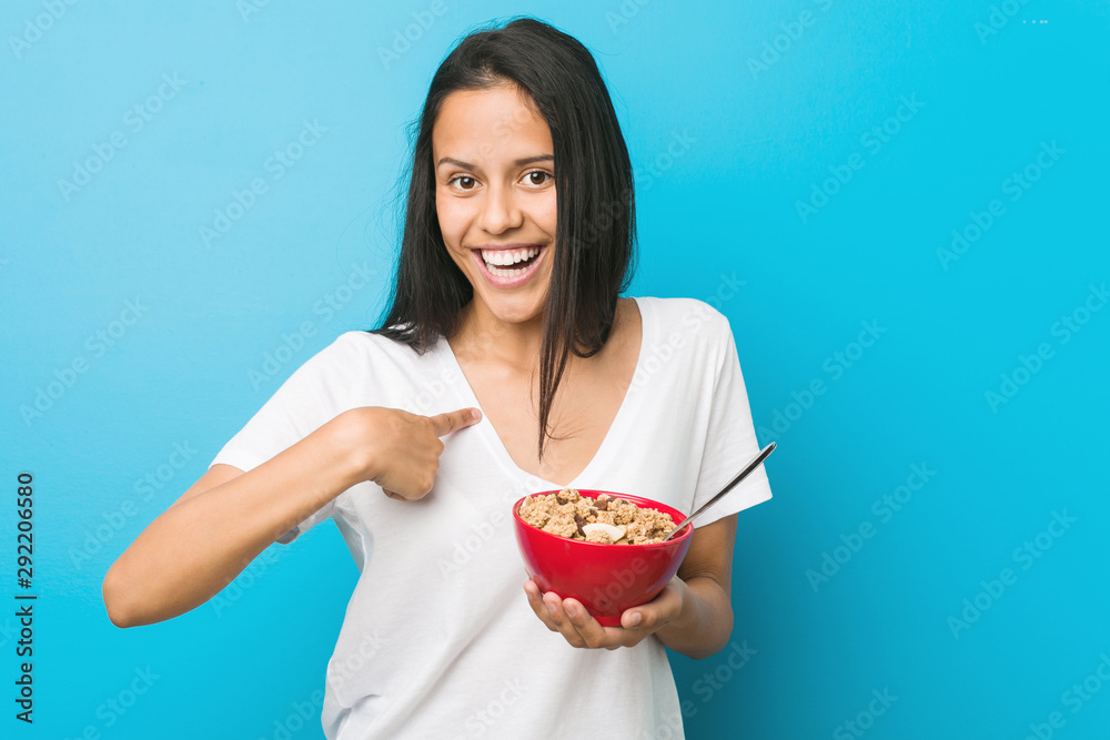 Young hispanic woman holding a cereal bowl surprised pointing at himself, smiling broadly. Young hispanic woman holding a cereal bowl surprised pointing at himself, smiling broadly.