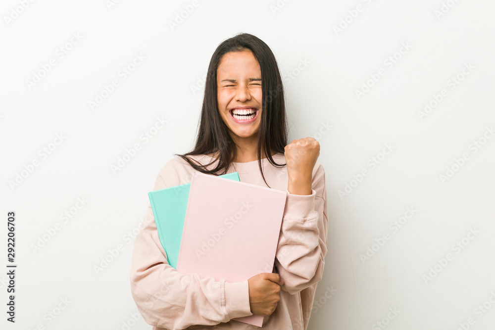 Young hispanic woman holding some notebooks cheering carefree and excited. Victory concept. Young hispanic woman holding some notebooks cheering carefree and excited. Victory concept.
