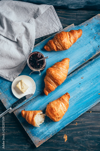 flat lay of delicious croissants with jam on dark wooden table