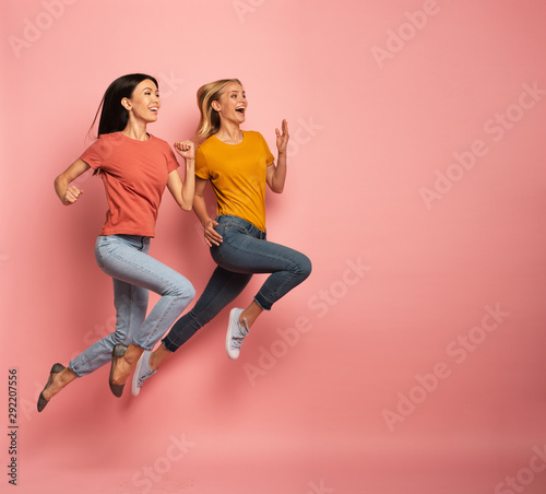 Two girls run fast. Concept of energy and vitality. Pink background