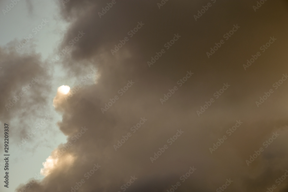 Obraz premium The sun and clouds on the blue sky. Cloudy weather with cumulus, dark clouds. Autumn day. A strong wind blows, the pressure is low, the threshold of rain.
