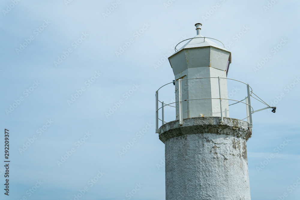 Lighthouse against a bright blue and grey sky. Summertime in Österlen, Sweden
