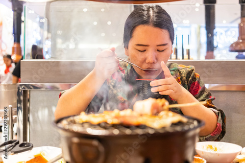 Woman holding spoon and bowl of soup, woman sipping soup fron spoon photo