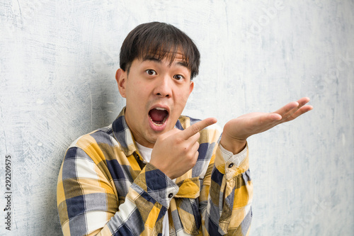 Cuadro en lienzo Young chinese man face closeup holding something with hand