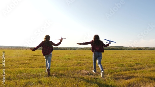 toy airplane in hands of girls they play on field. happy kids in a meadow with an airplane in hand. Dreams of flying. concept of a happy childhood. Silhouette of children playing on an airplane.