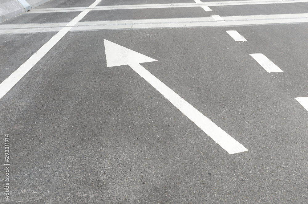 The white arrow symbol on an asphalt road, indicating direction of traffic o forward and turn left. For the symbol concept on the street, transportation concept, decision marking concept. The white arrow symbol on an asphalt road, indicating direction of traffic o forward and turn left. For the symbol concept on the street, transportation concept, decision marking concept.