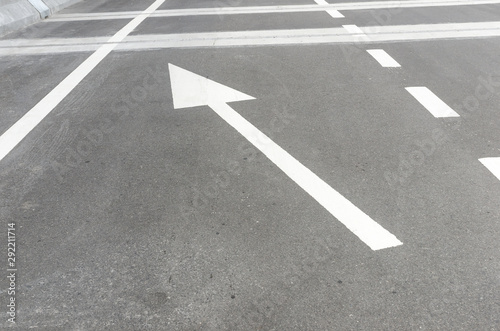 The white arrow symbol on an asphalt road, indicating direction of traffic o forward and turn left. For the symbol concept on the street, transportation concept, decision marking concept.