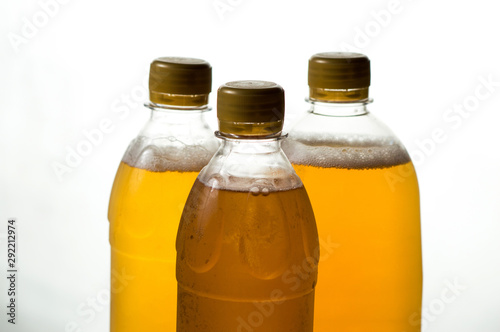 foamy beer in three transparent plastic bottles on a white background