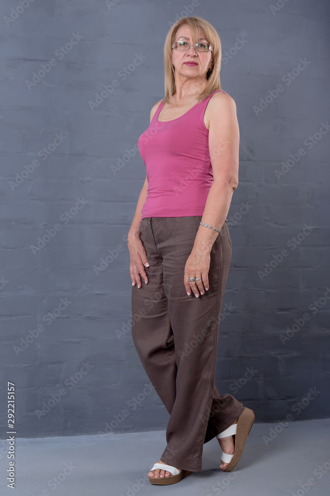 Beautiful mature full-length woman in a pink tank top and sweatpants. Beautiful mature full-length woman in a pink tank top and sweatpants.