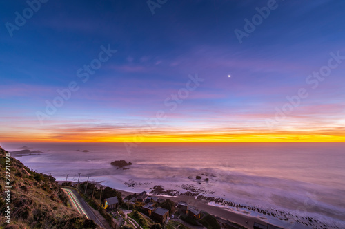 Fototapeta Naklejka Na Ścianę i Meble -  Idyllic scenery at Matanzas beach waves coming from the Pacific Ocean illuminated by a moody sky during twilight. Amazing sea landscape with a colorful sky and a waxing crescent Moon on a starry night