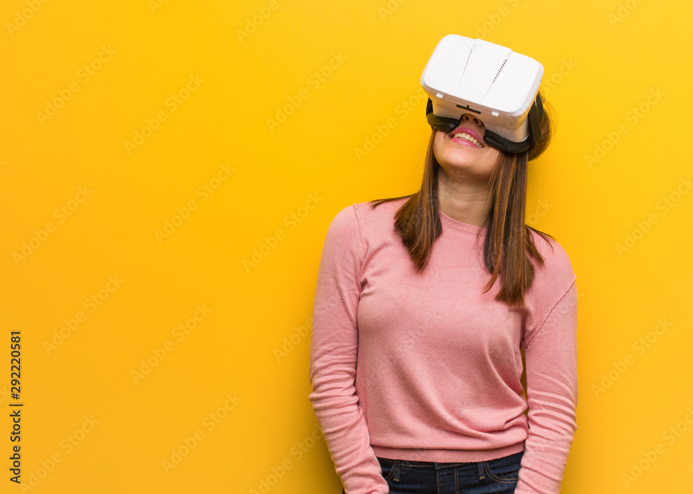 Young cute woman wearing a virtual reality googles cheerful with a big smile Young cute woman wearing a virtual reality googles cheerful with a big smile