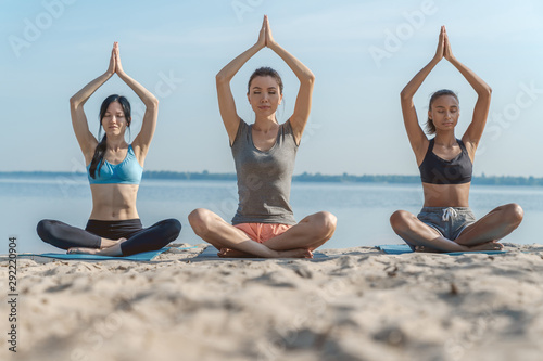 Group of young sporty girls practicing yoga lesson with woman instructor