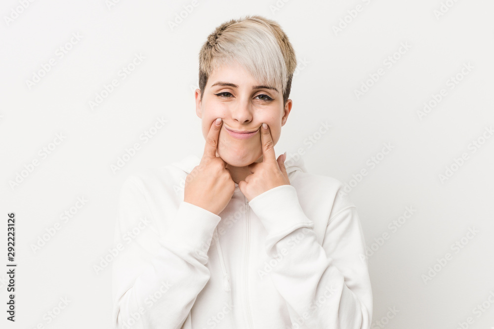 Young curvy woman wearing a white hoodie doubting between two options.