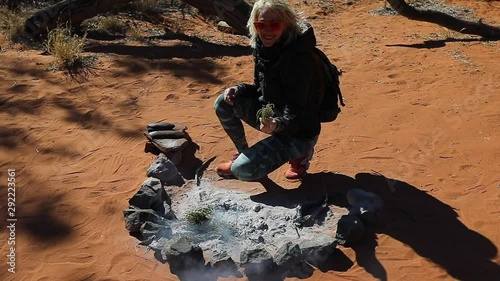 SLOW MOTION: Tourist burning the bush plants on fire and stones. Plants have special properties and during the smoking ceremony of the Indigenous Australians, plants are burned for purification. photo