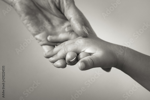 Female hand holding a small Childs hand. Giving love and care to a child concept. 